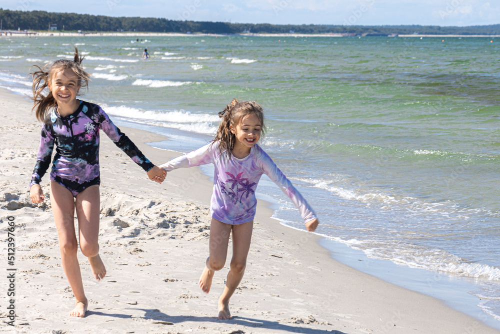 Cheerful little girls sisters play on the seashore. Cheerful little girls sisters play on the seashore.