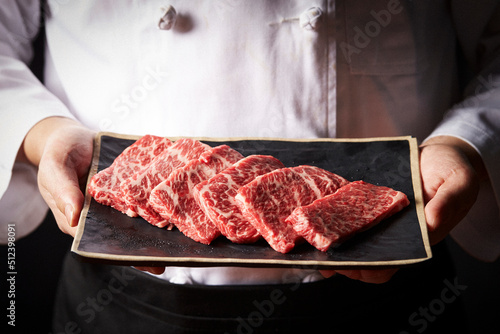 Chef holding fresh raw meat on plate