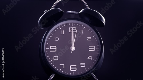 Closeup isolated shot on a dark background of a traditional analog alarm clock face, in lilac color, with its bells ringing as the time pointers reach 12 o’clock. photo