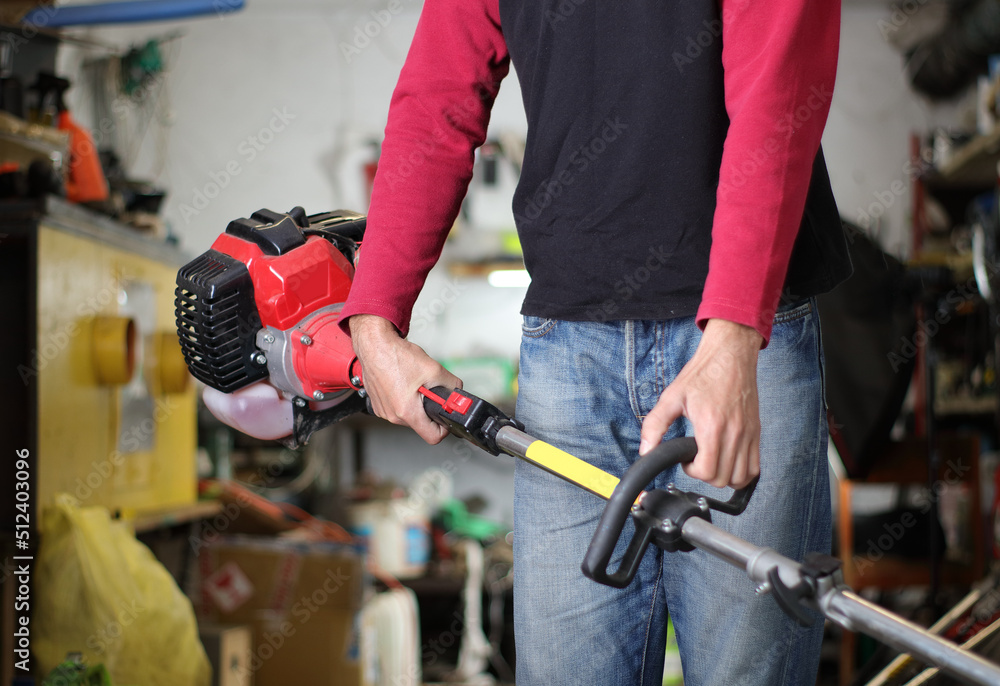 a person is holding a petrol brush cutter a person is holding a petrol brush cutter