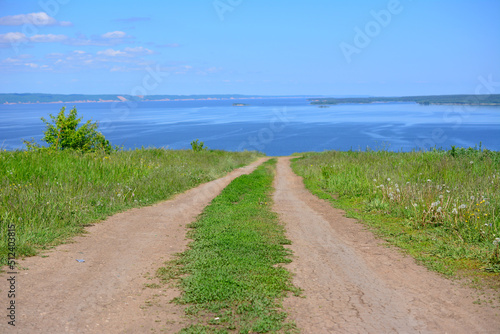 empty country road leading to the river from top of hill