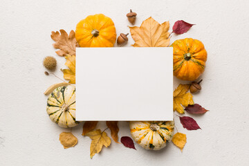 Autumn composition with paper blank and dried leaves with pumpkin on table. Flat lay, top view, copy space