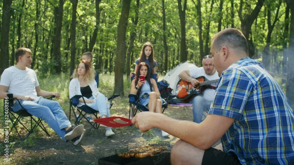 happy company, mom, dad, son, daughter and their friends are having a picnic in the forest area. family camping in summer.resting with tent in forest city park. happy company, mom, dad, son, daughter and their friends are having a picnic in the forest area. family camping in summer.resting with tent in forest city park.