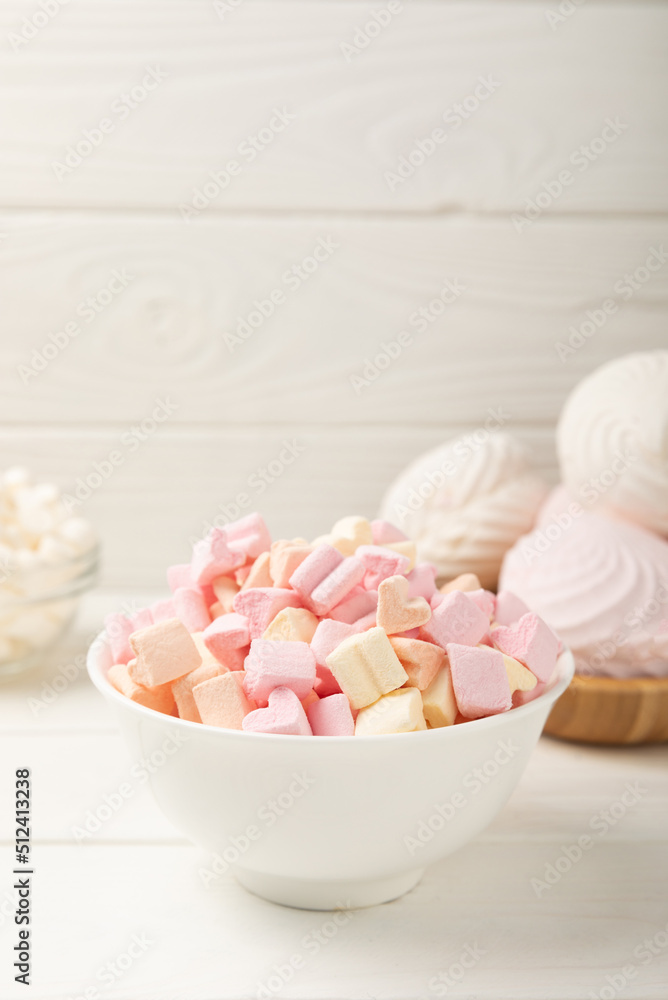 Many different marshmallows in bowls and jars on a white textured wood. White and fruit marshmallow. Sweets and snacks for a snack. Chewing candies close-up. Copy space. Place for text. Many different marshmallows in bowls and jars on a white textured wood. White and fruit marshmallow. Sweets and snacks for a snack. Chewing candies close-up. Copy space. Place for text.