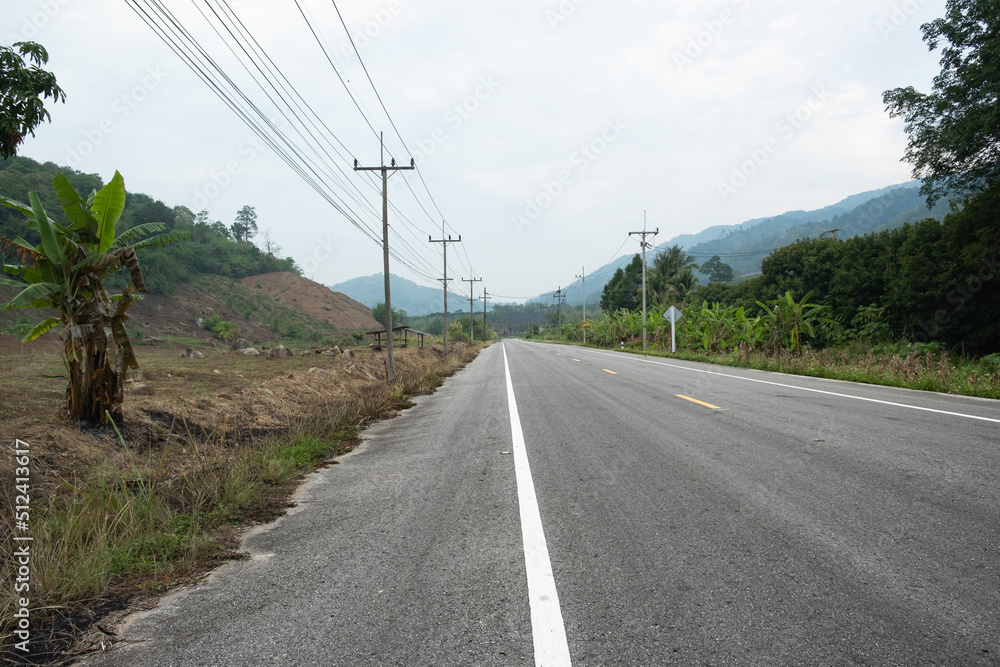 Paved road Thailand.The asphalt road on both sides of the road is covered with grass. Paved road Thailand.The asphalt road on both sides of the road is covered with grass.