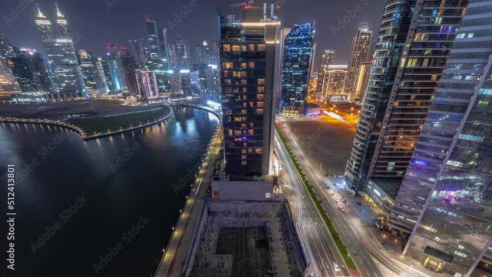 Cityscape of skyscrapers in Dubai Business Bay with water canal aerial night timelapse looking down panoramic view. Modern skyline with illuminated towers and waterfront. A center of international Cityscape of skyscrapers in Dubai Business Bay with water canal aerial night timelapse looking down panoramic view. Modern skyline with illuminated towers and waterfront. A center of international