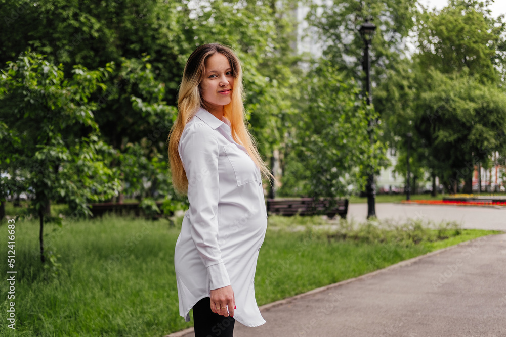 Pregnant young woman walking on street looking at camera outdoors Pregnant young woman walking on street looking at camera outdoors