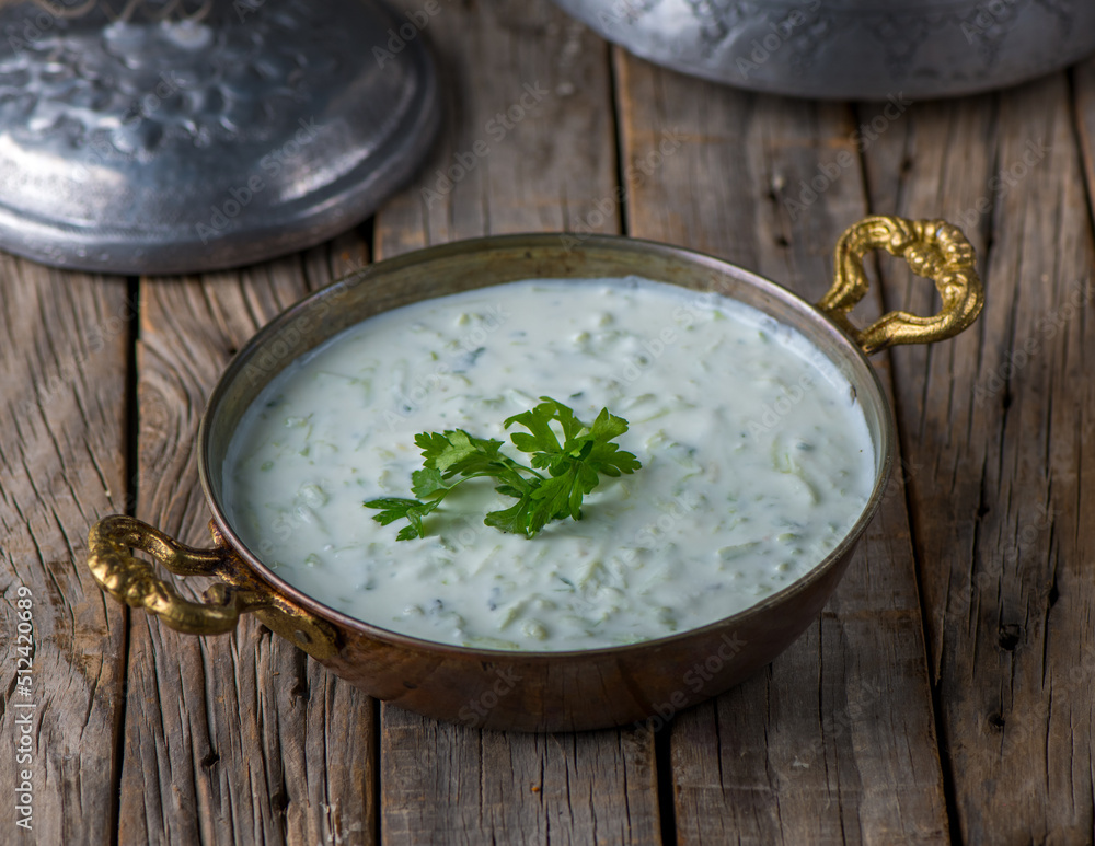 Fresh Cucumber Yoghurt raita served in dish side view on wooden table background Fresh Cucumber Yoghurt raita served in dish side view on wooden table background