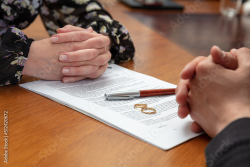 Divorce signature, marriage dissolution document. Wedding ring and agreement on lawyer office table photo