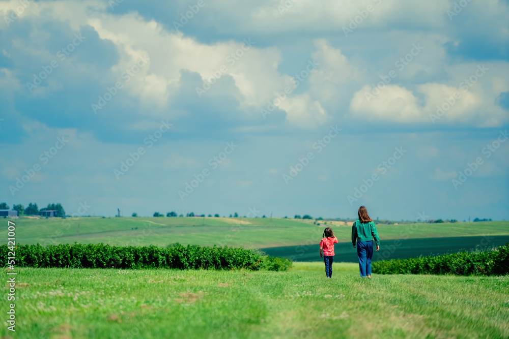 Two young girls sisters walking in the poppy field. Childhood, nature, happiness and healthy lifestyle concept.