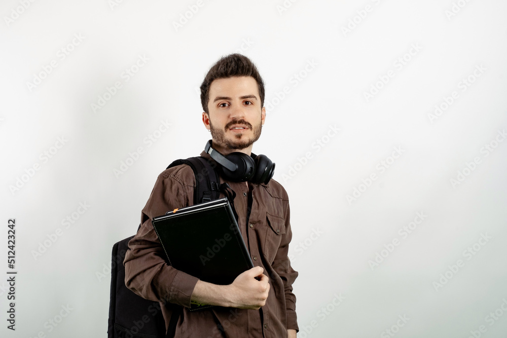 Handsome caucasian man wearing casual clothes posing isolated over white background student with books and backpack and looking at the camera. High school university college concept.