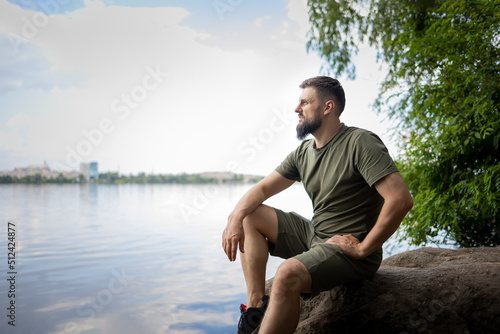 A man sits on a rock by the river