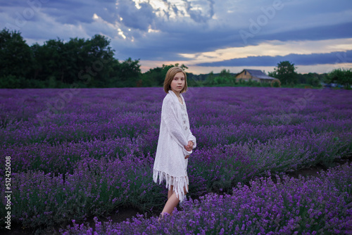 Fototapeta Naklejka Na Ścianę i Meble -  Teenage girl enjoys the scenery of lavender field. Dreamy teenager walking among purple flowers on the beautiful sunset. Calm landscape, escape to beauty of nature, summer travel and vacation