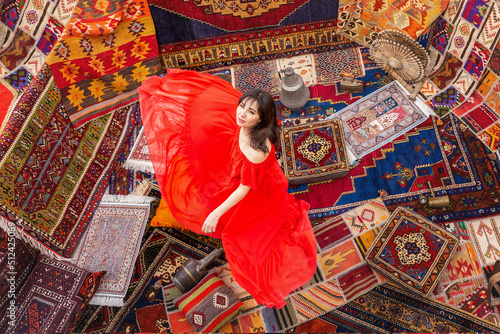 Girl in a red dress on Turkish carpets. View from above .