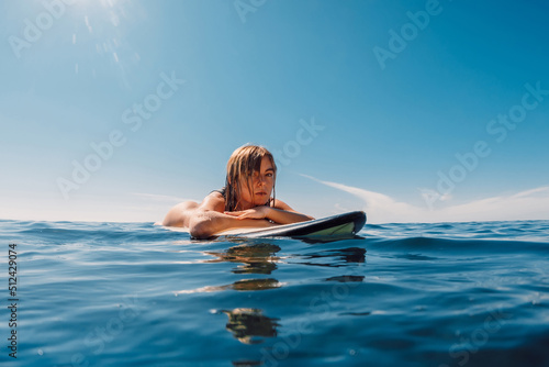 Portrait of attractive blonde surf girl in ocean during surfing