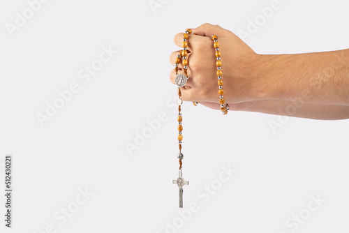 Folded hands of a young man holding a rosary during a pray isolated on white background
