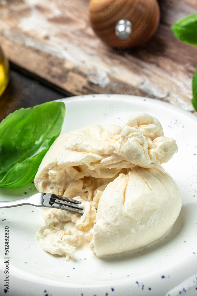 fresh soft white burrata cheese ball made from mozzarella and cream from Apulia, Italian Mediterranean cuisine, vertical image. top view. place for text fresh soft white burrata cheese ball made from mozzarella and cream from Apulia, Italian Mediterranean cuisine, vertical image. top view. place for text