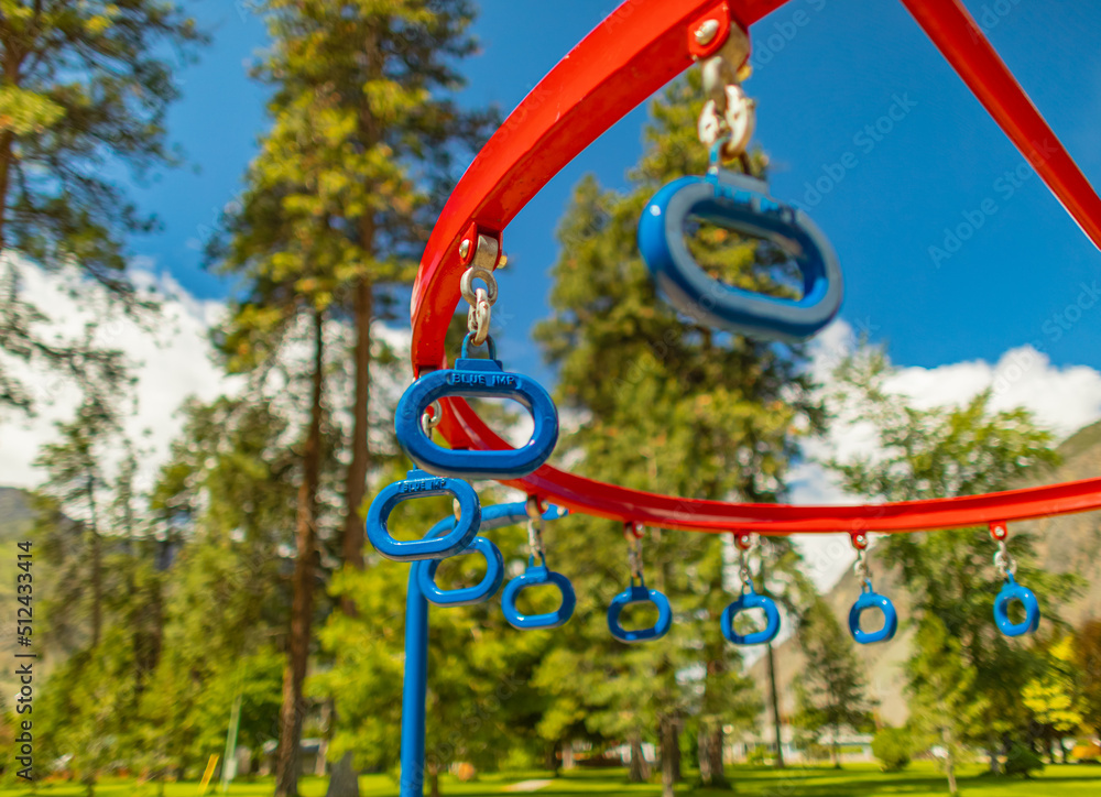 Hanging monkey bars in a summer playground in a citypark. Row of blue hanging rings in a park.