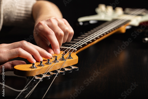 The hands of a guitarist changing strings on an electric guitar photo