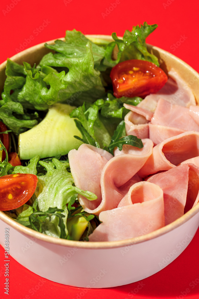 Fresh vegetable salad with slices of ham , cherry tomatoes, avocado, mix lettuce leaves. Ham salad. Take away food. Isolated Fresh vegetable salad with slices of ham , cherry tomatoes, avocado, mix lettuce leaves. Ham salad. Take away food. Isolated
