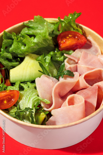 Fresh vegetable salad with slices of ham , cherry tomatoes, avocado, mix lettuce leaves. Ham salad. Take away food. Isolated