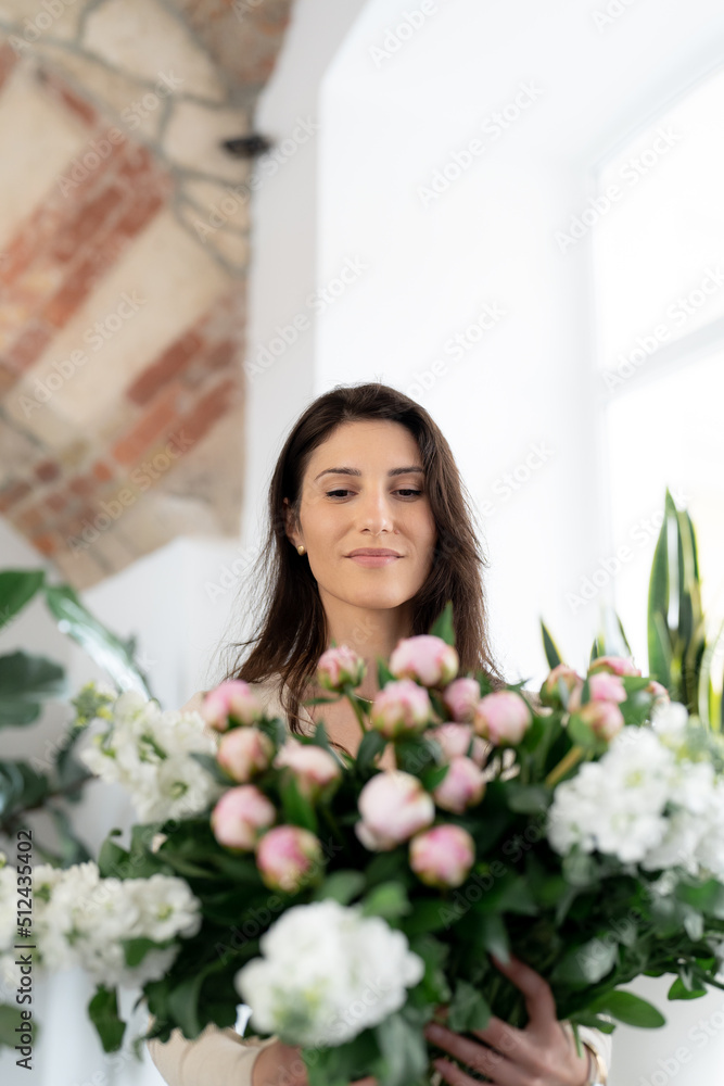 Positive woman holding a huge bouquet of flowers in her office. Birthday present smile.