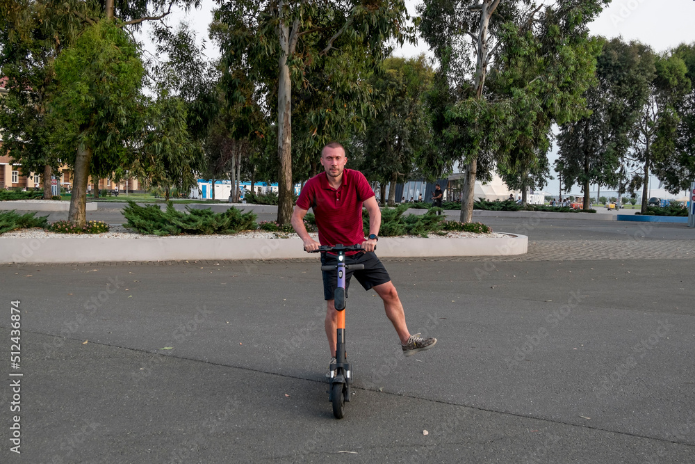 Obraz premium Attractive man riding a kick scooter at cityscape background.