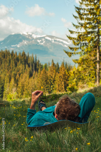 A man lies on the grass against the backdrop of mountains in the forest outdoor recreation travel mountaineering tourism happiness,carpathian lifestyle vacation, active recreation, relaxing 