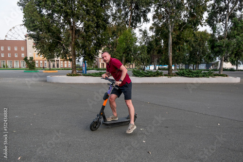 Attractive man riding a kick scooter at cityscape background.