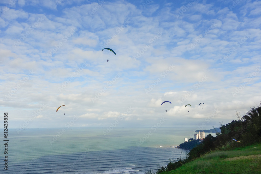 paragliders flying on cloudy sky above Santos city beach in Brazil
