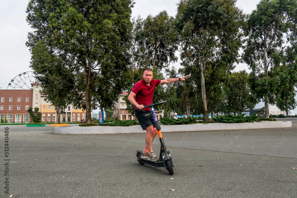 Obraz premium Attractive man riding a kick scooter at cityscape background.