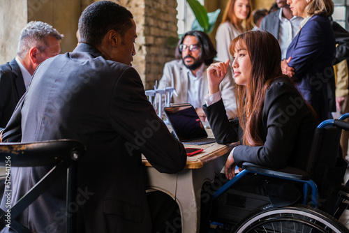Conversation between a young man and a girl in a wheelchair at a company meeting