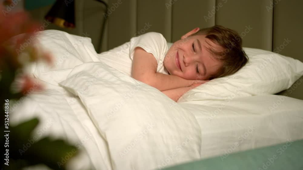 Sixyearold boy sleeps sweetly in his crib and smiles in his sleep