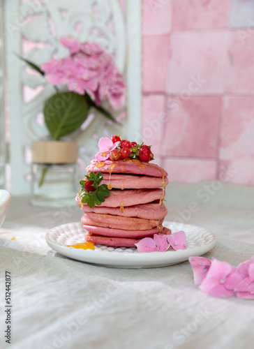 Stack of pink pancakes with strawberry. Pink colourful pancakes with berries and honey . Breakfast