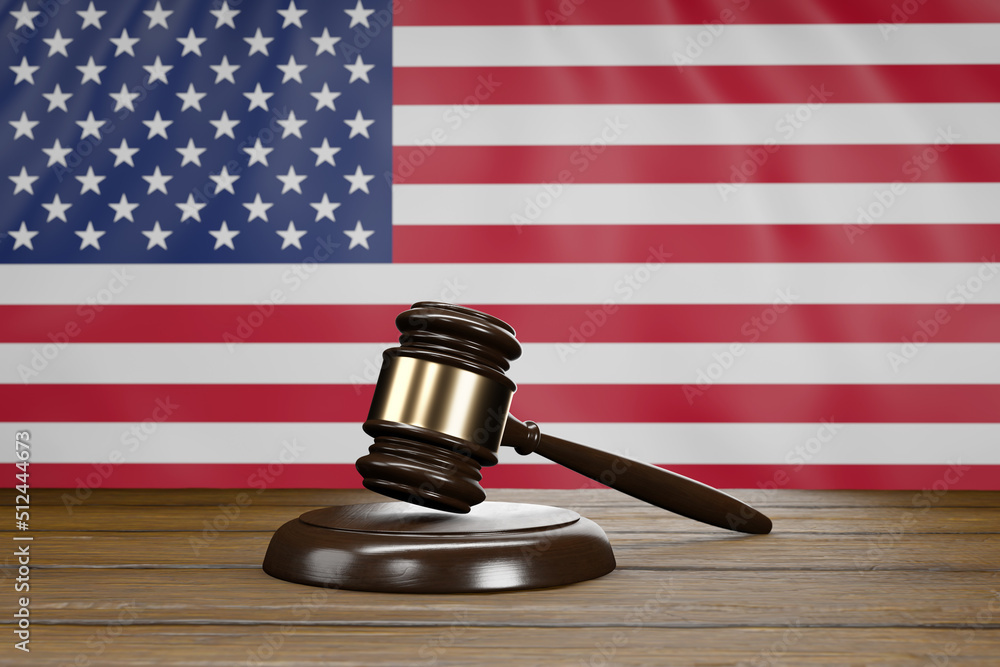 Small hammer gavel of judges of courts placed on a wooden table with USA flag as background.