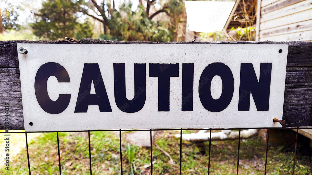 Caution Sign on a Wooden Fence with Black Letters Caution Sign on a Wooden Fence with Black Letters