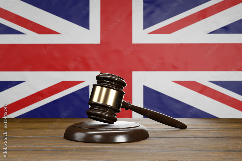 Small hammer gavel of judges of courts placed on a wooden table with UK flag as background