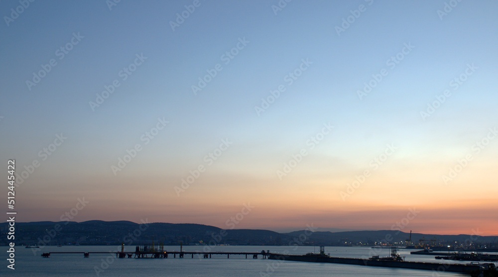 Evening city on the seacoast. Pink sunset. Clear blue sky. Black Sea. Novorossiysk. Krasnodar Region. Russia. Postcard. Screensaver on the monitor. Background. Banner.