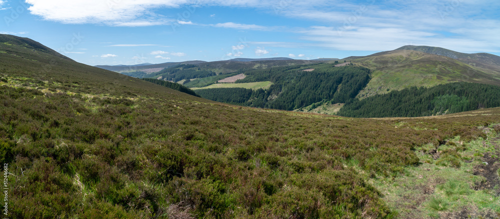 Panoramic view. Looking down a valley towards a town in Wicklow National Park in wicklow. Staturated colors.. Ideal day for hiking. Panoramic view. Looking down a valley towards a town in Wicklow National Park in wicklow. Staturated colors.. Ideal day for hiking.