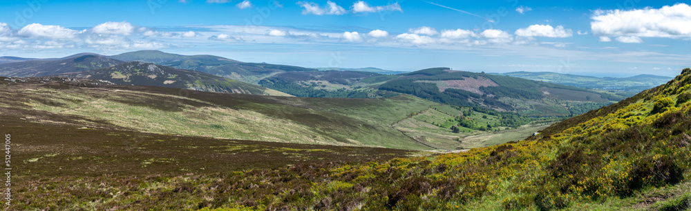 Panoramic view. Looking down a valley towards a town in Wicklow National Park in wicklow. Staturated colors.. Ideal day for hiking.