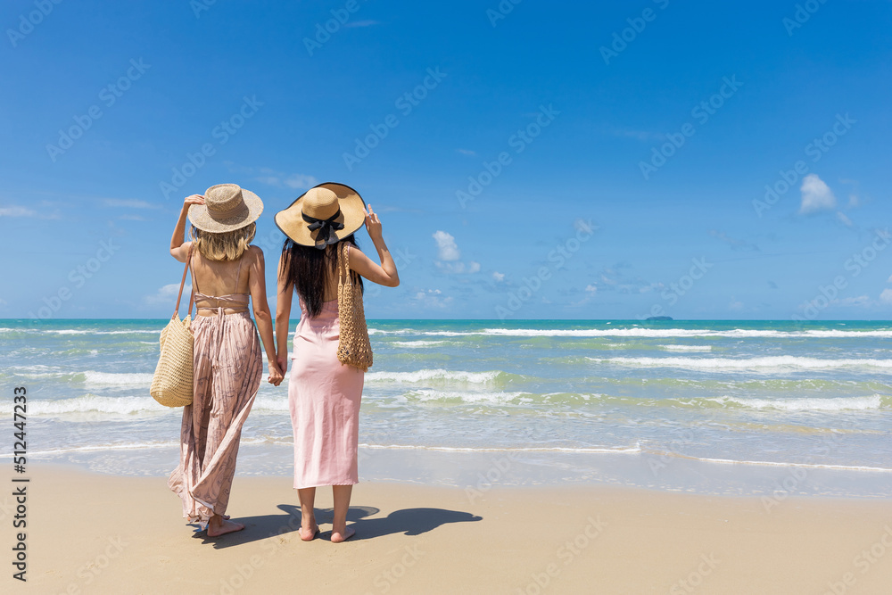 back view women couple standing on the beach during summer vacation back view women couple standing on the beach during summer vacation