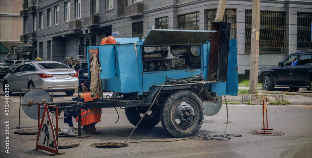 Welding machine on wheels on a city road. Repair of the city sewer system.