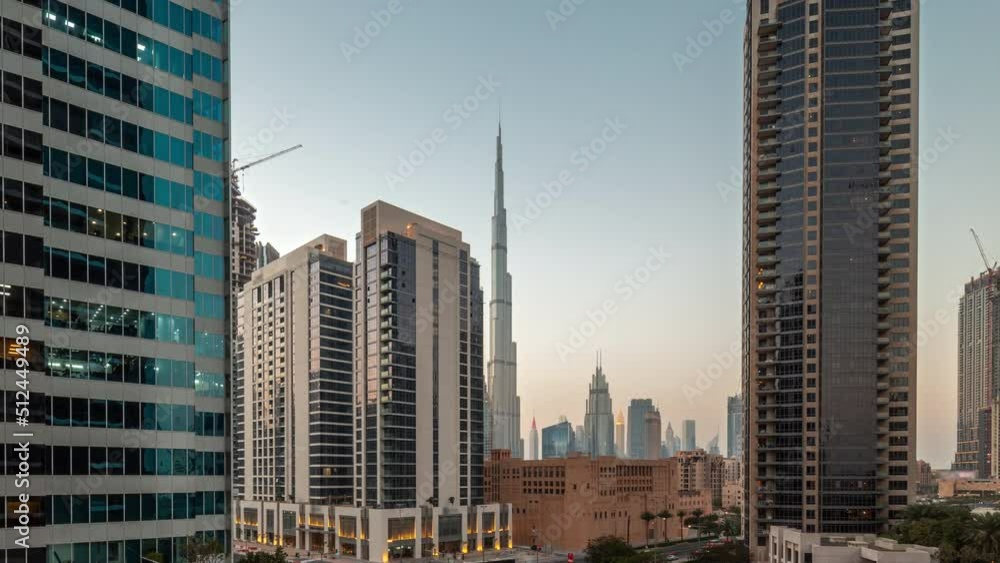 Aerial panoramic view to Dubai downtown and difc skyscrapers with busy traffic on intersection in Business bay district day to night transition timelapse after sunset. Aerial panoramic view to Dubai downtown and difc skyscrapers with busy traffic on intersection in Business bay district day to night transition timelapse after sunset.