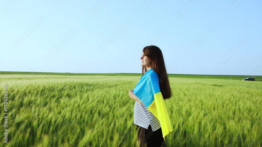girl cheerfully runs through a wheat field with the flag of Ukraine girl cheerfully runs through a wheat field with the flag of Ukraine