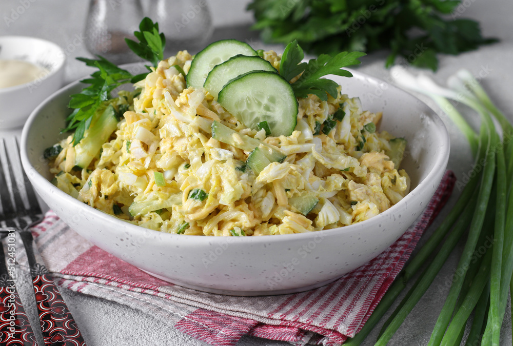 Salad with chicken, chinese cabbage, cucumber, boiled eggs and cheese in white bowl on light gray background Salad with chicken, chinese cabbage, cucumber, boiled eggs and cheese in white bowl on light gray background