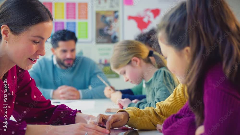 Elementary school students with female teacher using digital tablets in classroom lesson - shot in slow motion Elementary school students with female teacher using digital tablets in classroom lesson - shot in slow motion