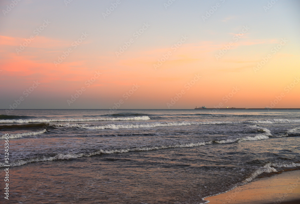 Waves in sea on sunset background. Waves in sea during storm and wind. Wave from the sea goes on land to the beach. Splashing Waves in ocean, background, texture. Wave at Rising Storm. Seashore.