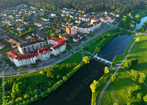 Townhouses and multi-floor home near river. River in city on sunrise, aerial view. Suburb houses and multi-storey residential buildings near river in Minsk, Belarus. Cottages and wooden suburb house.
