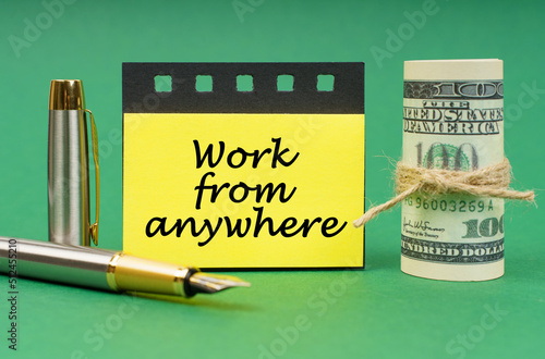 фотографія On a green surface, a pen, dollars, a notepad and yellow stickers with the inscr