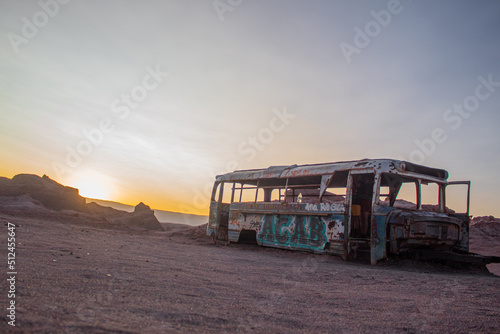 Autobús desgastado y abandonado en medio del desierto en un atardecer de verano, Atacama, Chile.